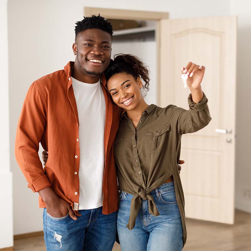 Young African american couple embracing, showing the key of their new home